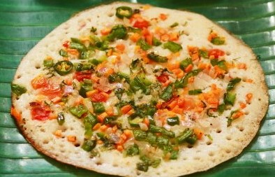 Thick rice pancake topped with onions, tomatoes, carrots, green peas and green chilies